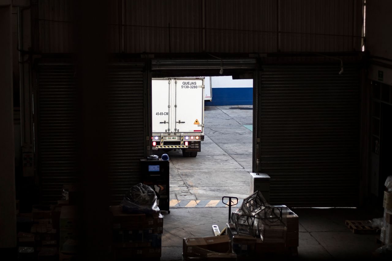 Free A delivery worker with a hand trolley managing a box shipment outside a warehouse. Stock Photo