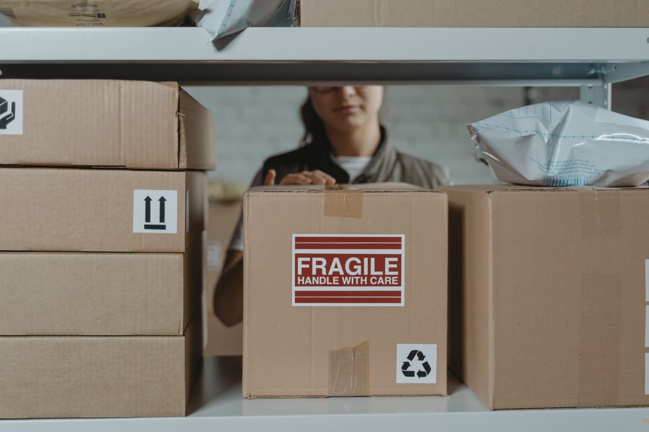 Free A person organizing fragile cardboard boxes in a warehouse setting. Stock Photo
