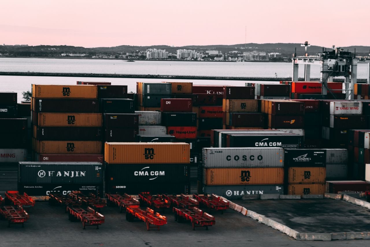 Free A bustling container yard at a seaport with shipping containers stacked and ready for transport at twilight. Stock Photo